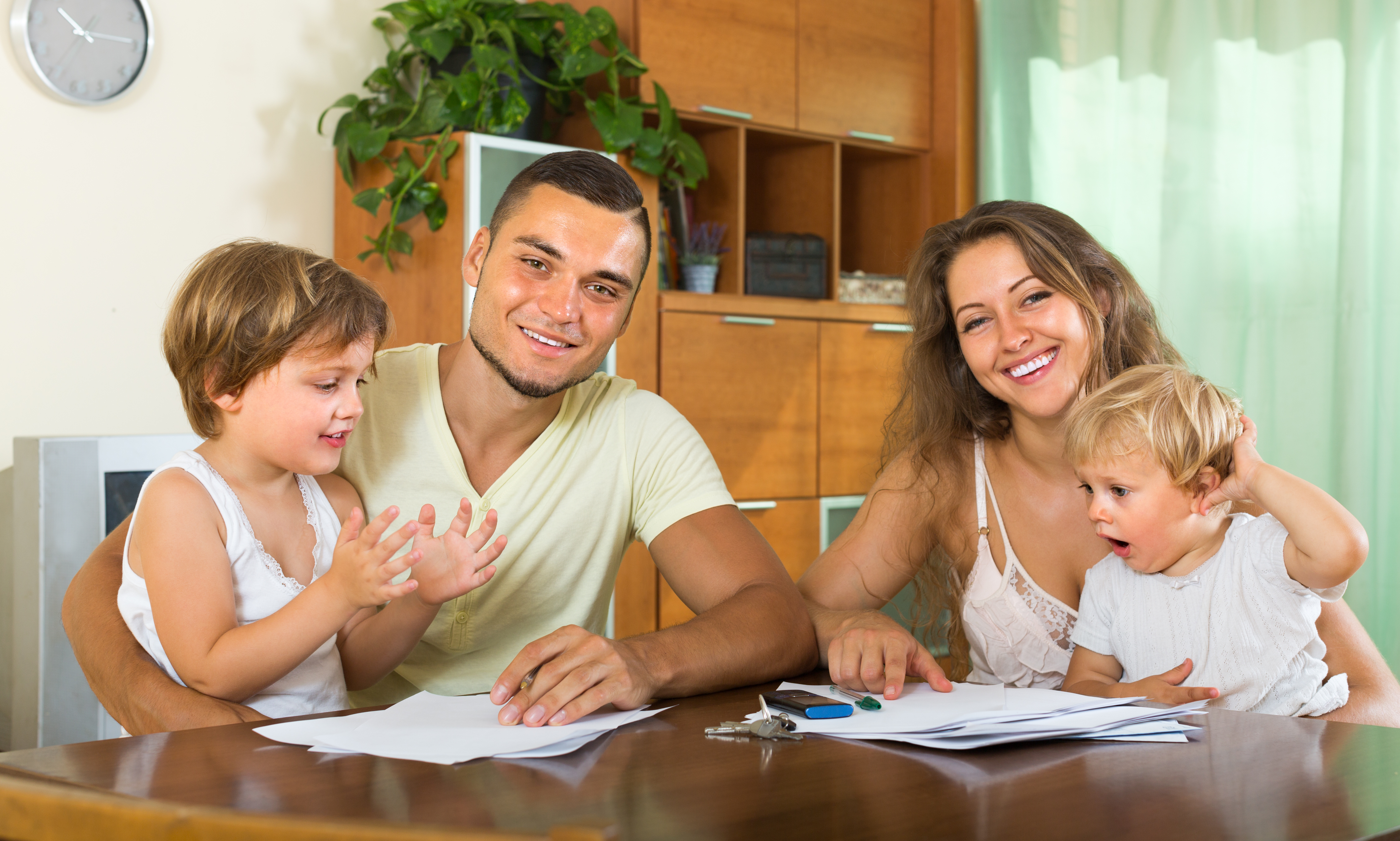 Young parents with little children buying insurance and smiling