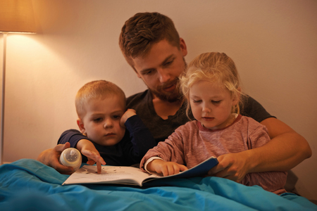 A father reading a bedtime story to his kids